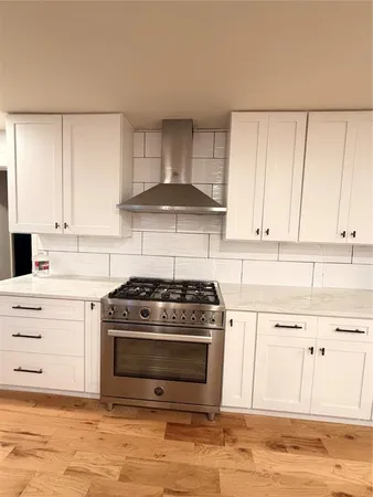 a kitchen with granite countertop white cabinets and a stove
