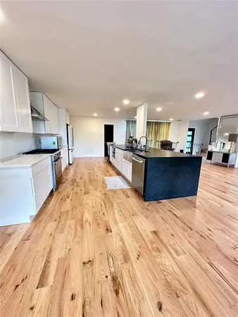 a large kitchen with stainless steel appliances kitchen island a large counter top space a stove and cabinets