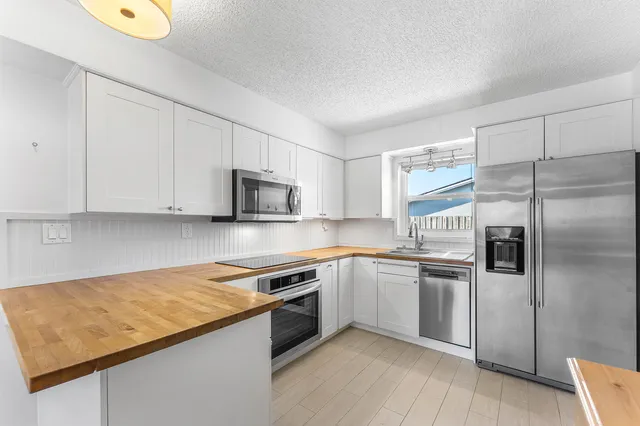 a kitchen with stainless steel appliances granite countertop a sink and a refrigerator