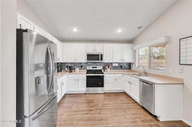 a kitchen with granite countertop a refrigerator stove top oven and sink