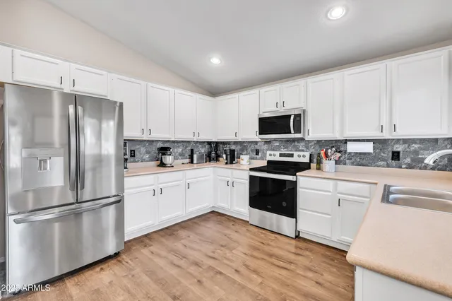 a kitchen with granite countertop a refrigerator stove and microwave