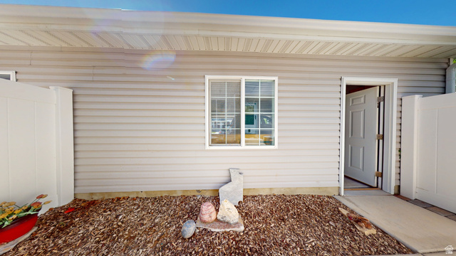 1674 Eastridge Road Price, UT 84501 - Photo 29 of 34 Exterior featuring horizontal siding, white trim windows, a white privacy fence, an entryway, and a ground covering of wood chips