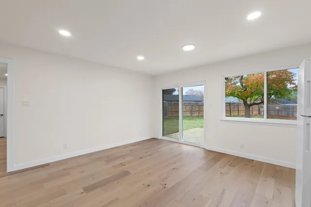 a view of an empty room with wooden floor and windows