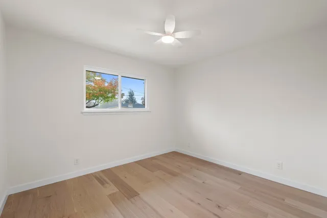 an empty room with wooden floor and ceiling fan