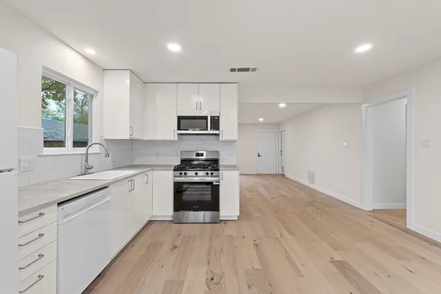 a kitchen with stainless steel appliances a sink stove and cabinets