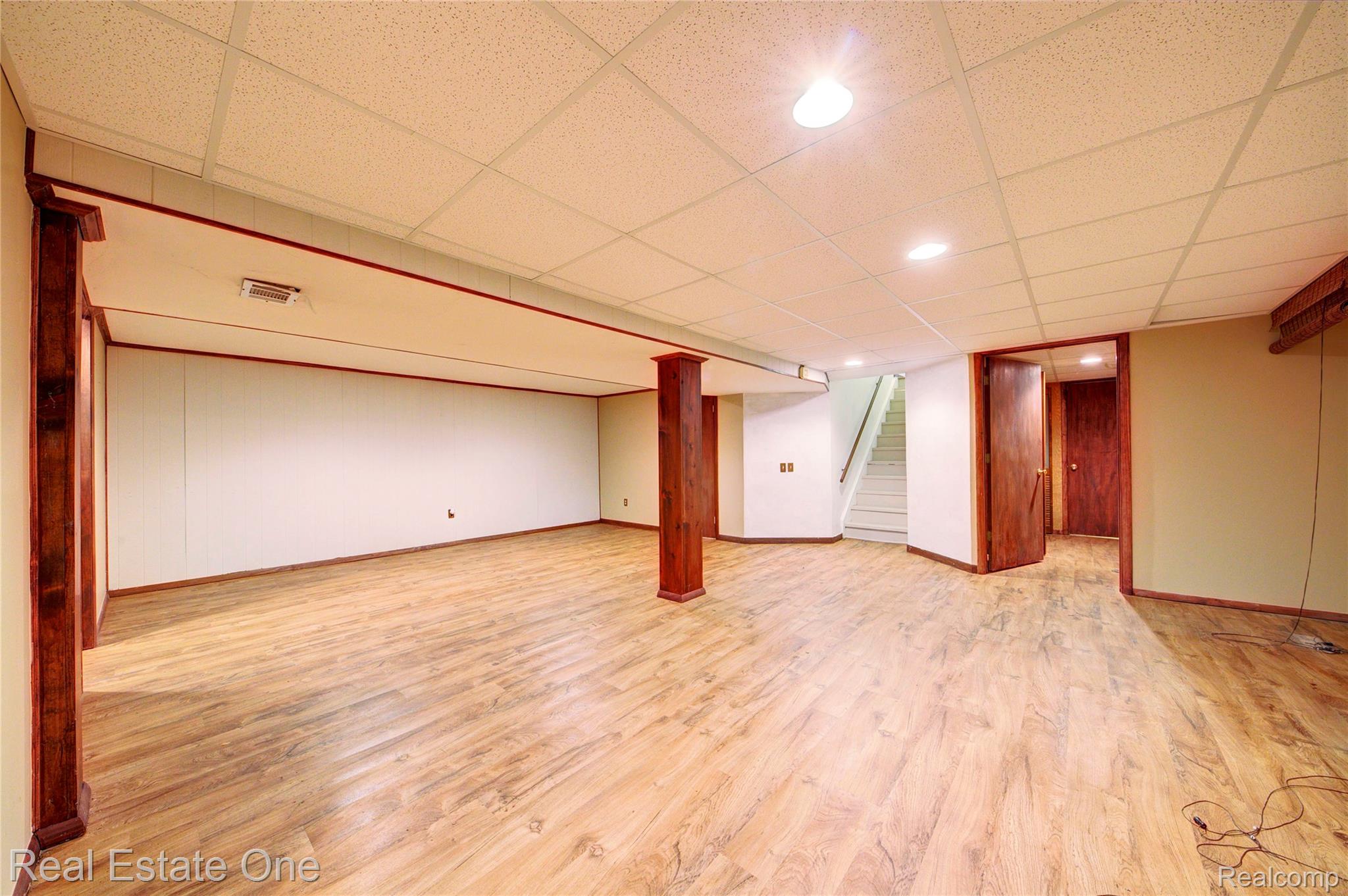 3125 West Commerce Road Milford, MI 48380 - Photo 45 of 63 Spacious finished basement featuring wood-finish flooring, recessed lighting, drop ceiling, and wood-trimmed support columns