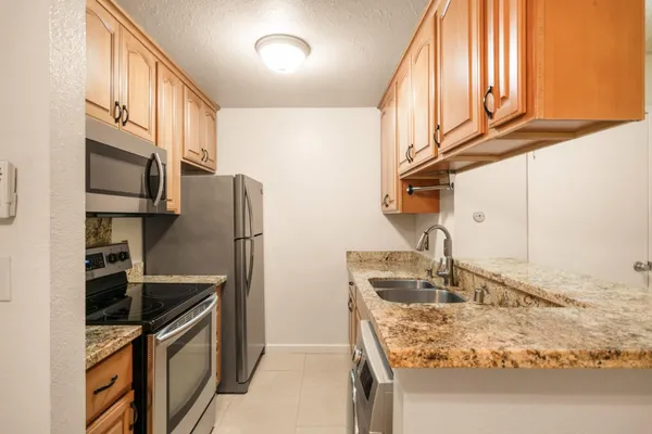 a kitchen with stainless steel appliances granite countertop a sink a stove and a refrigerator