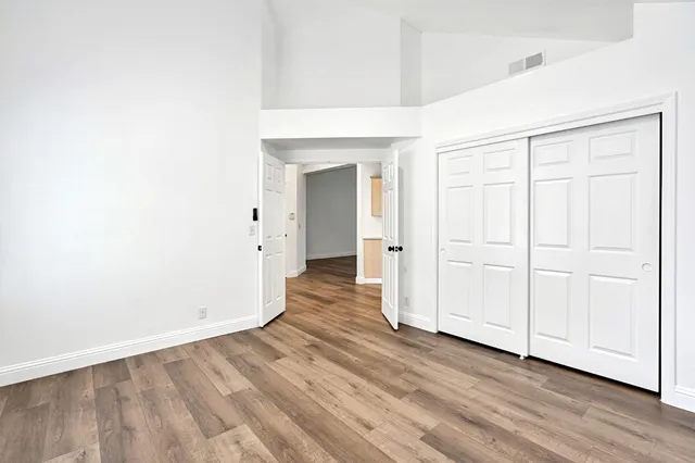 an empty room with wooden floor & closet area