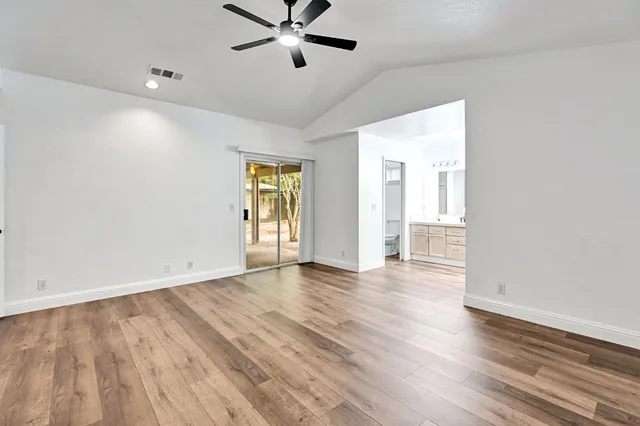 an empty room with wooden floor and windows