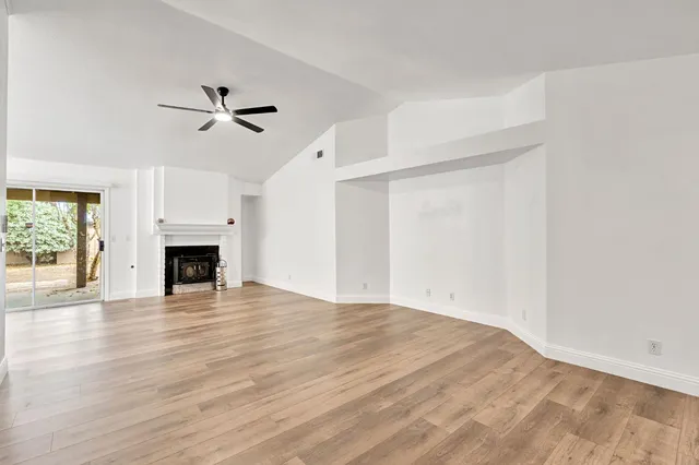 a view of empty room with wooden floor and fireplace