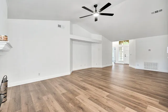 a view of empty room with wooden floor and fan