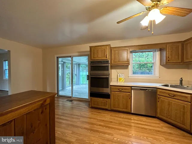 a kitchen with stainless steel appliances granite countertop a sink cabinets and wooden floor