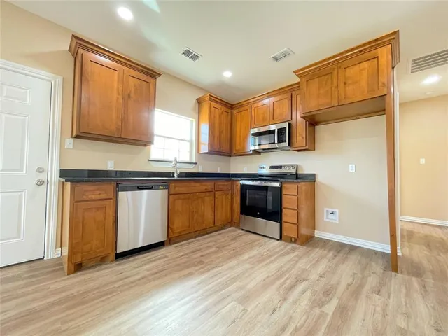 a kitchen with stainless steel appliances granite countertop a stove a sink dishwasher and a refrigerator