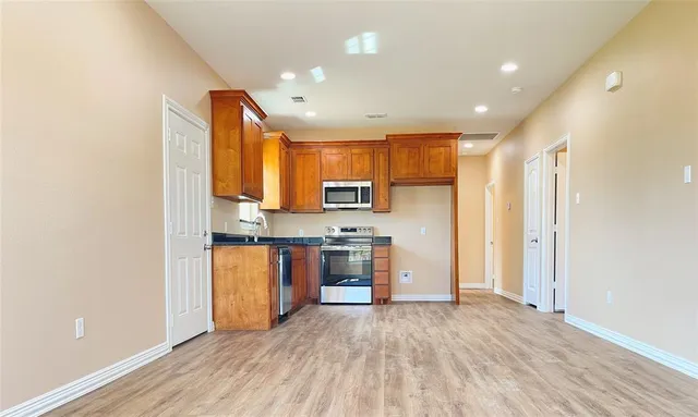 a view of kitchen with stainless steel appliances granite countertop a refrigerator and a stove top oven