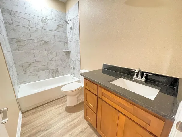a bathroom with a granite countertop sink a toilet a mirror and bathtub