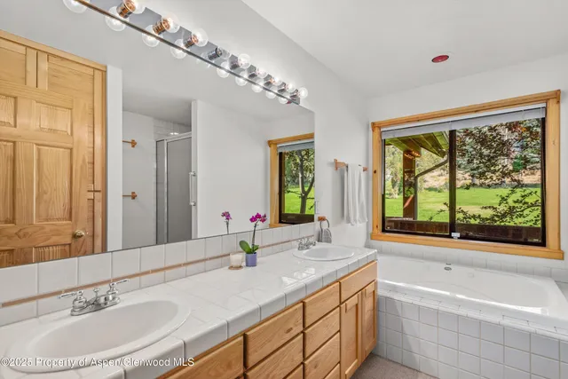 a bathroom with a double vanity sink bathtub and next to a window
