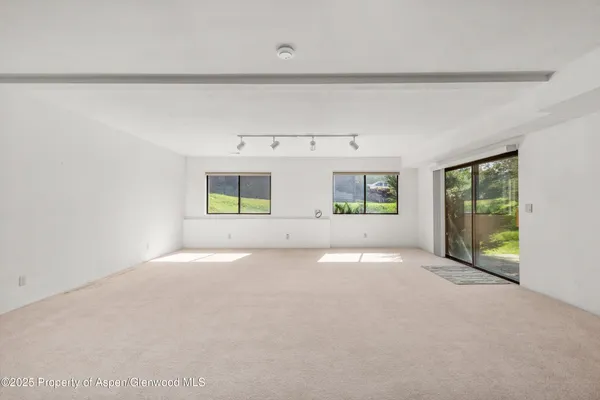 a view of an empty room with a window and kitchen view