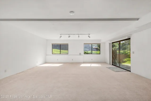 a view of an empty room with a window and kitchen view