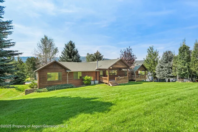 a view of a house with a big yard and large trees