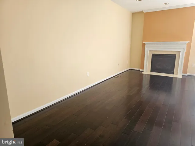 a view of an empty room with wooden floor and a fireplace