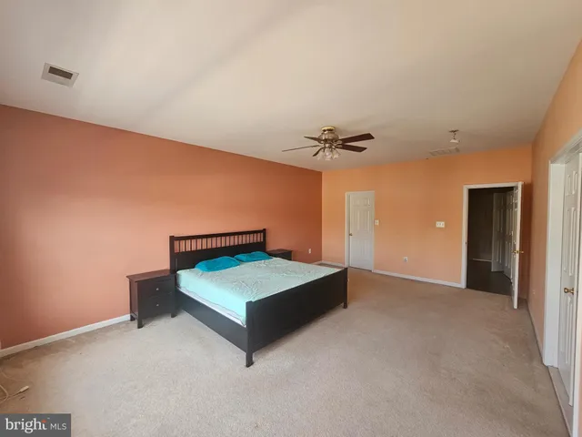 a spacious bedroom with a bed and a chandelier fan