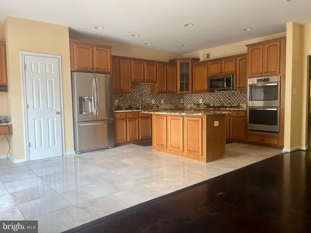 a kitchen with stainless steel appliances granite countertop a refrigerator and a stove top oven