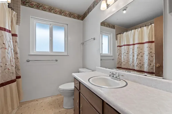 a bathroom with a granite countertop sink toilet and a mirror