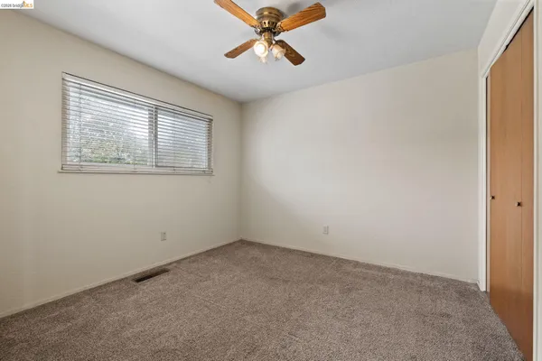 an empty room with windows and fan