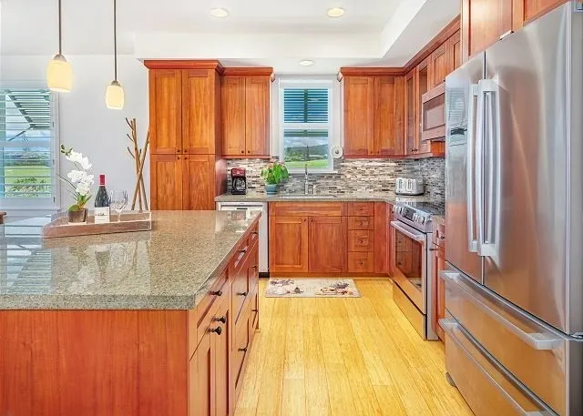 a kitchen with stainless steel appliances granite countertop a sink a stove and a wooden floors