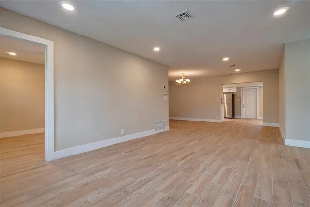 an empty room with wooden floor and natural light