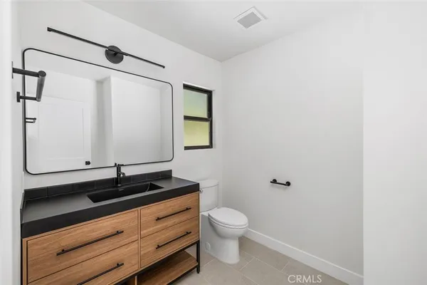a bathroom with a granite countertop sink toilet and mirror