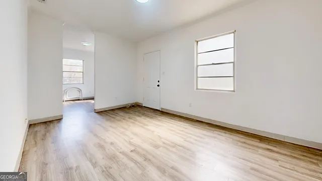 an empty room with wooden floor and windows