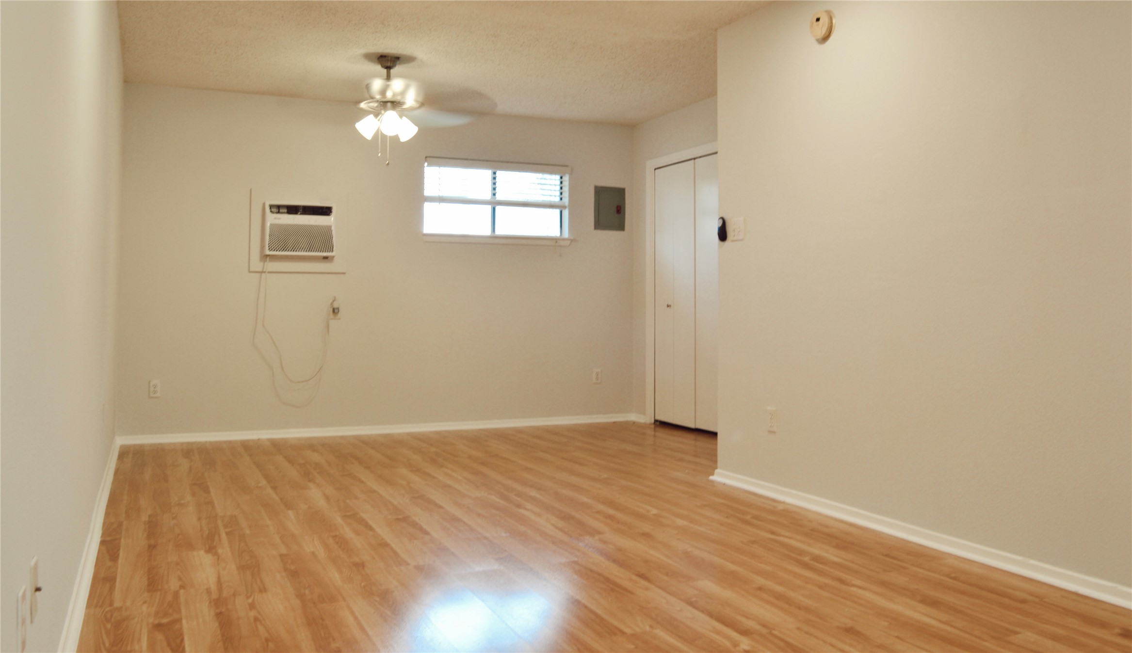 5701 Woodrow Avenue, Unit 203 Austin, TX 78756 - Photo 4 of 9 an empty room with wooden floor chandelier fan and windows