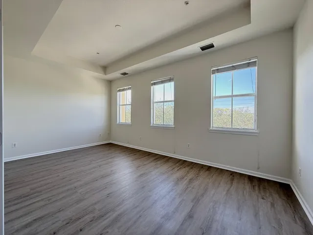a view of an empty room with wooden floor and window
