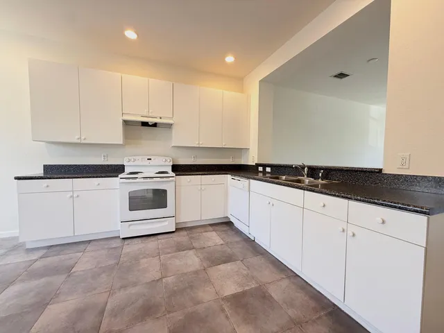 a white kitchen with granite countertop white cabinets and white appliances