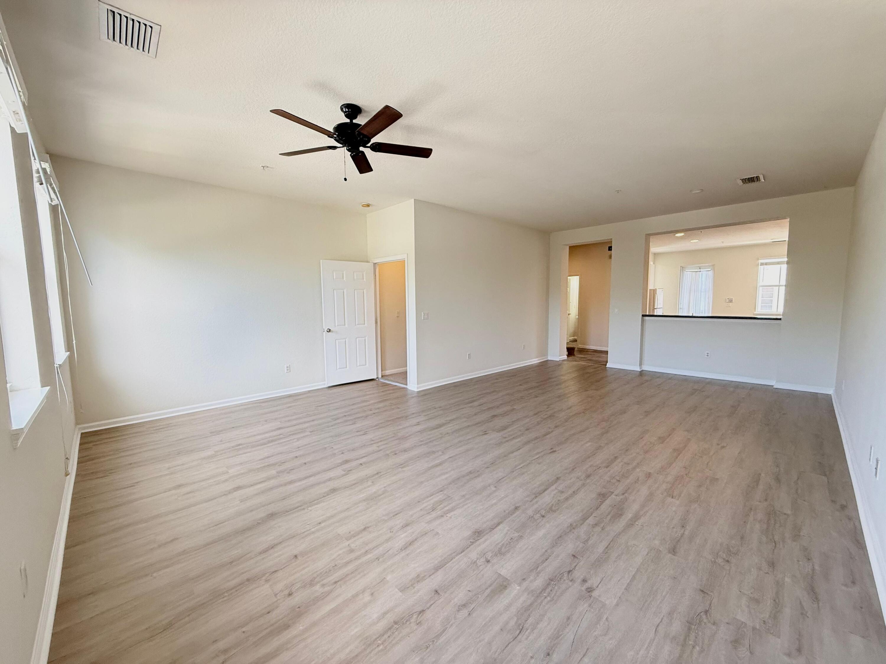 425 Greenwich Circle, Unit 206 Jupiter, FL 33458 - Photo 10 of 30 an empty room with wooden floor a ceiling fan and windows