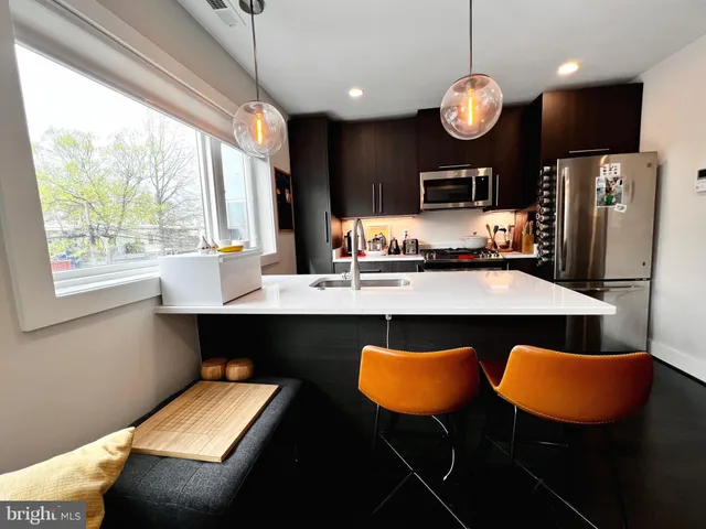 a kitchen with stainless steel appliances granite countertop a table chairs sink and wooden floor