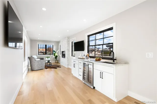 a large white kitchen with stainless steel appliances a large counter top a couch and a flat screen tv