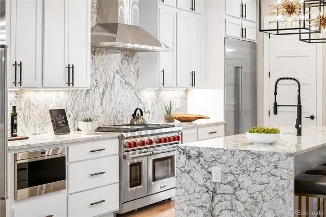 a kitchen with stainless steel appliances granite countertop a stove a sink and a white wooden cabinets