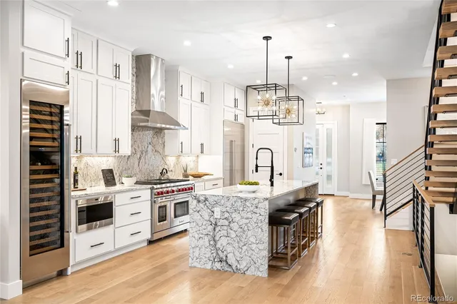 a large kitchen with stainless steel appliances granite countertop a stove and a wooden floors