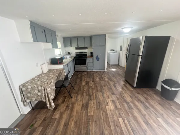 a kitchen with stainless steel appliances a refrigerator a sink dishwasher a stove and white cabinets with wooden floor