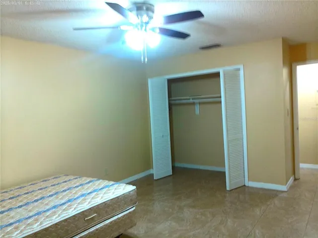 an empty room with a chandelier fan and a bathroom