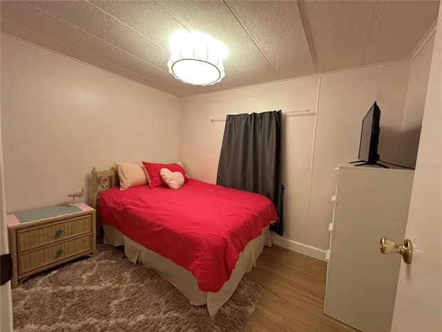 a bedroom with a bed and a flat tv screen on the dresser
