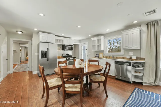 a kitchen with stainless steel appliances kitchen island granite countertop a dining table chairs and sink