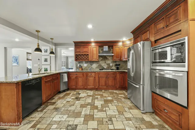 a room with stainless steel appliances kitchen island granite countertop a refrigerator and a stove