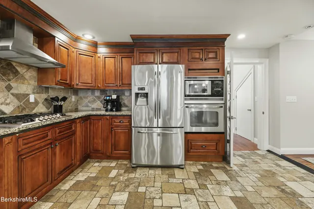 a kitchen with stainless steel appliances granite countertop a refrigerator stove and sink