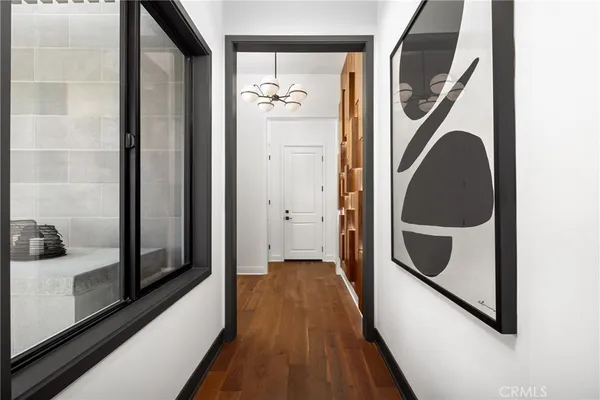 a view of a hallway with wooden floor and a bathroom