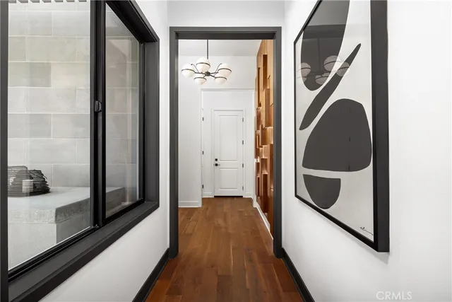 a view of a hallway with wooden floor and a bathroom