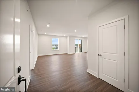 a kitchen with stainless steel appliances a stove a sink dishwasher a refrigerator and white cabinets with wooden floor