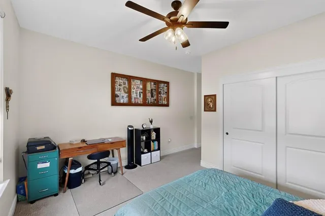 a view of a livingroom with workspace and a ceiling fan